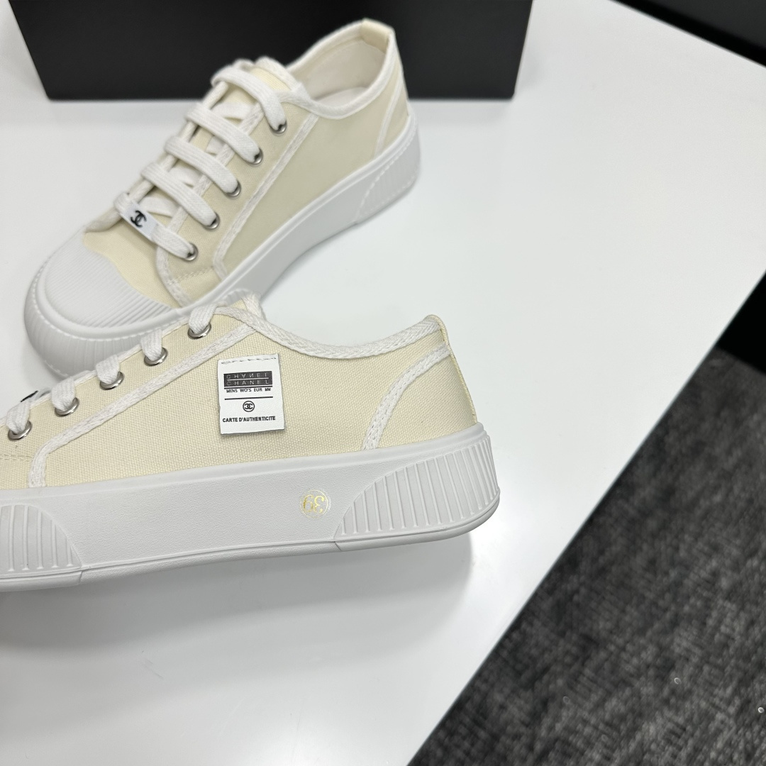 Pair of premium cream canvas low-top sneakers with a chunky white rubber sole and designer logo details displayed on a black box. - Hình 6