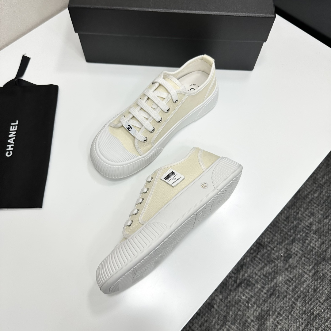 Pair of premium cream canvas low-top sneakers with a chunky white rubber sole and designer logo details displayed on a black box. - Hình 5