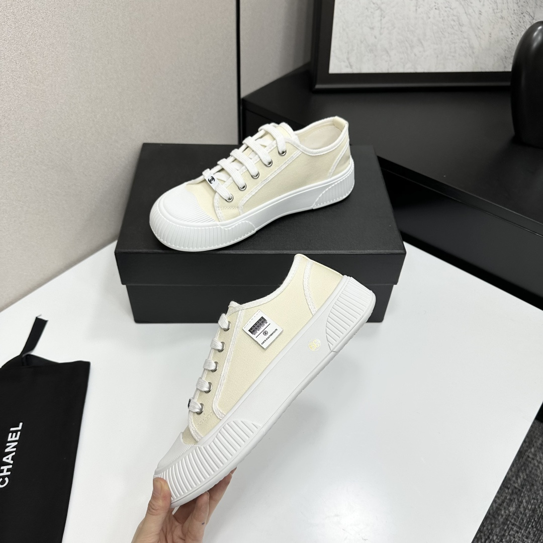 Pair of premium cream canvas low-top sneakers with a chunky white rubber sole and designer logo details displayed on a black box. - Hình 3