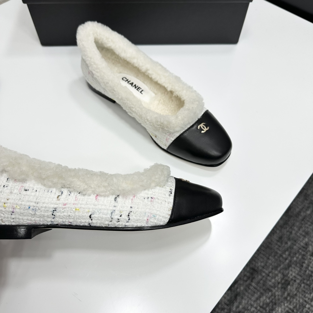 Luxury Chanel white tweed ballet flats with black leather toe caps and white faux fur lining displayed on a black designer box. - Hình 2