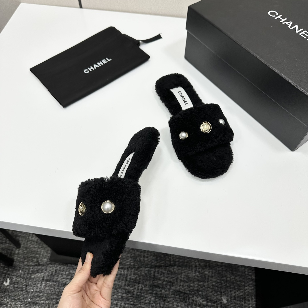Luxurious black Chanel shearling slides featuring a pearl and gold CC logo displayed on a designer box. - Hình 7