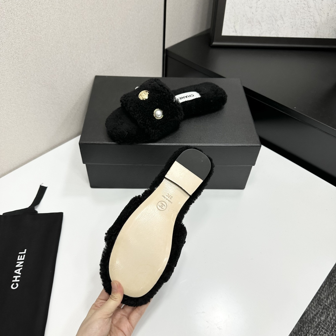 Luxurious black Chanel shearling slides featuring a pearl and gold CC logo displayed on a designer box. - Hình 4