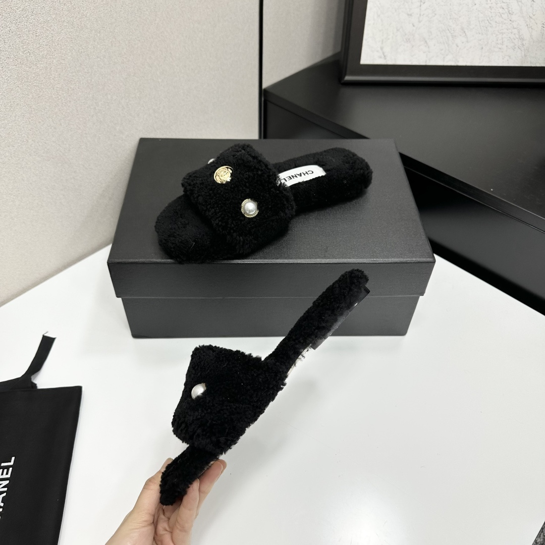 Luxurious black Chanel shearling slides featuring a pearl and gold CC logo displayed on a designer box. - Hình 3