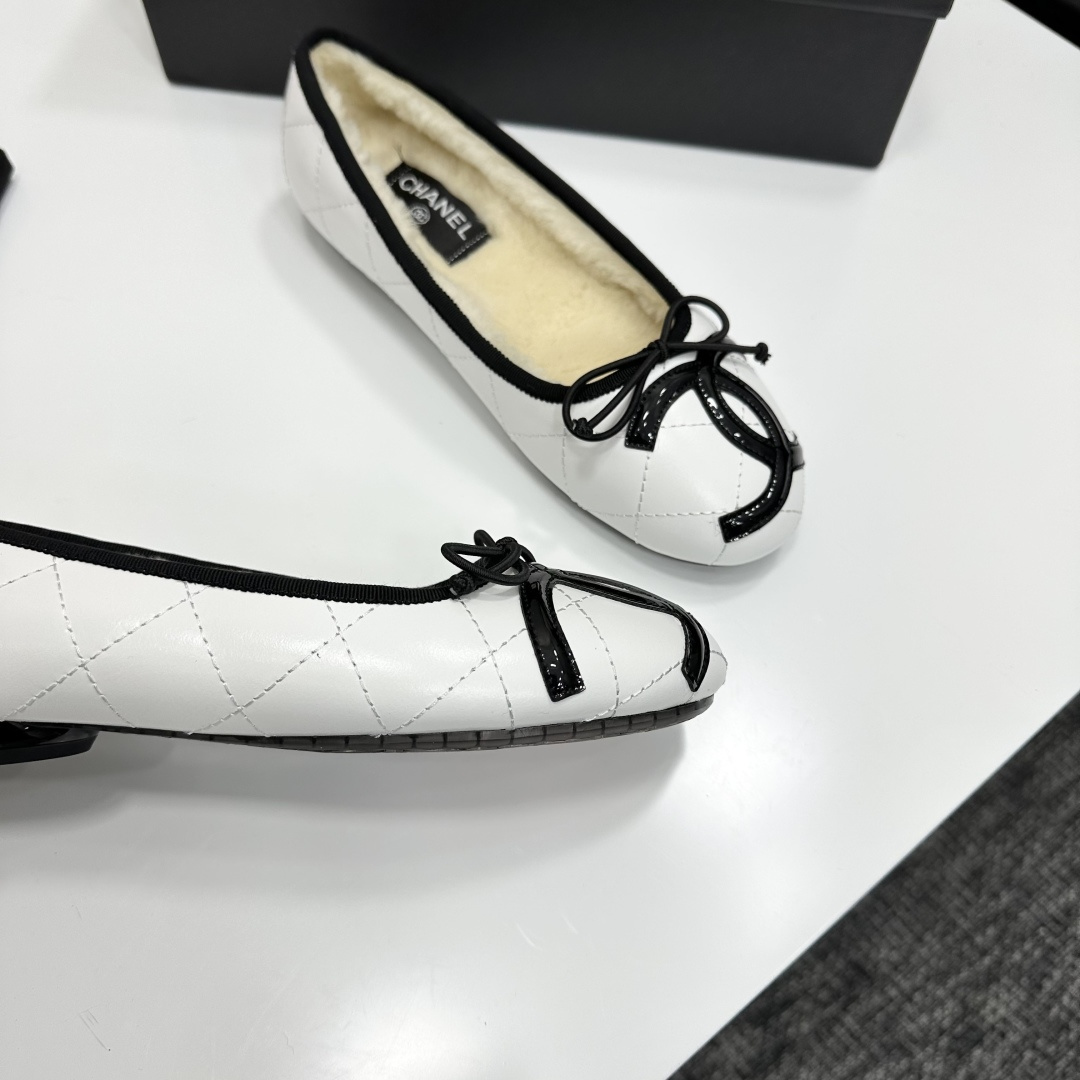 Pair of white quilted leather ballet flats with black trim and shearling lining on a black display box - Hình 9