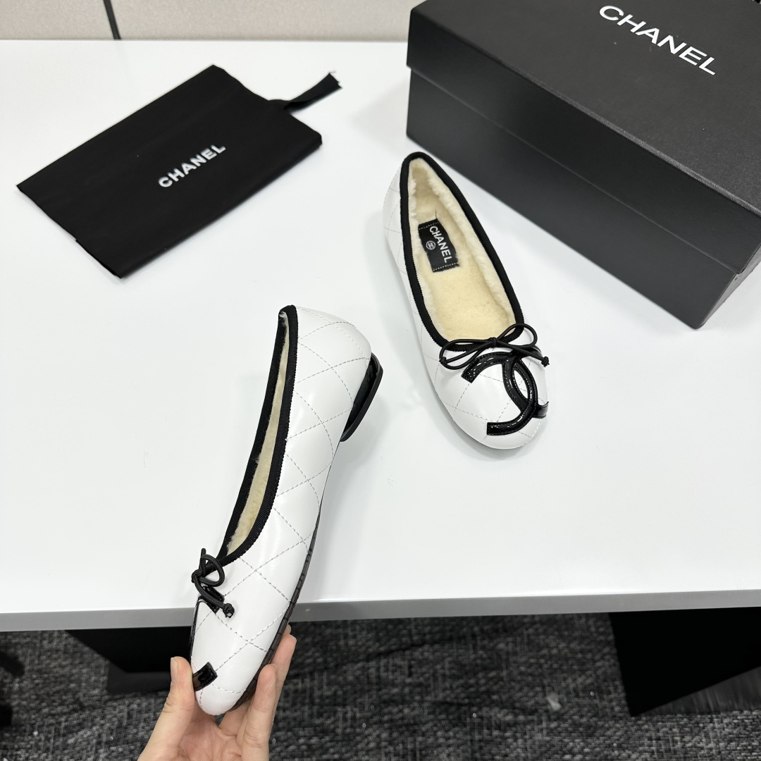 Pair of white quilted leather ballet flats with black trim and shearling lining on a black display box - Hình 8