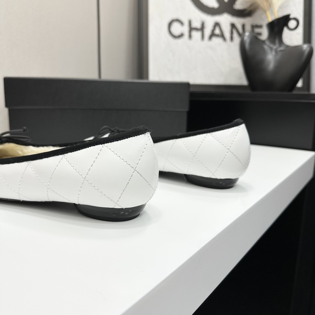 Pair of white quilted leather ballet flats with black trim and shearling lining on a black display box - Hình 7