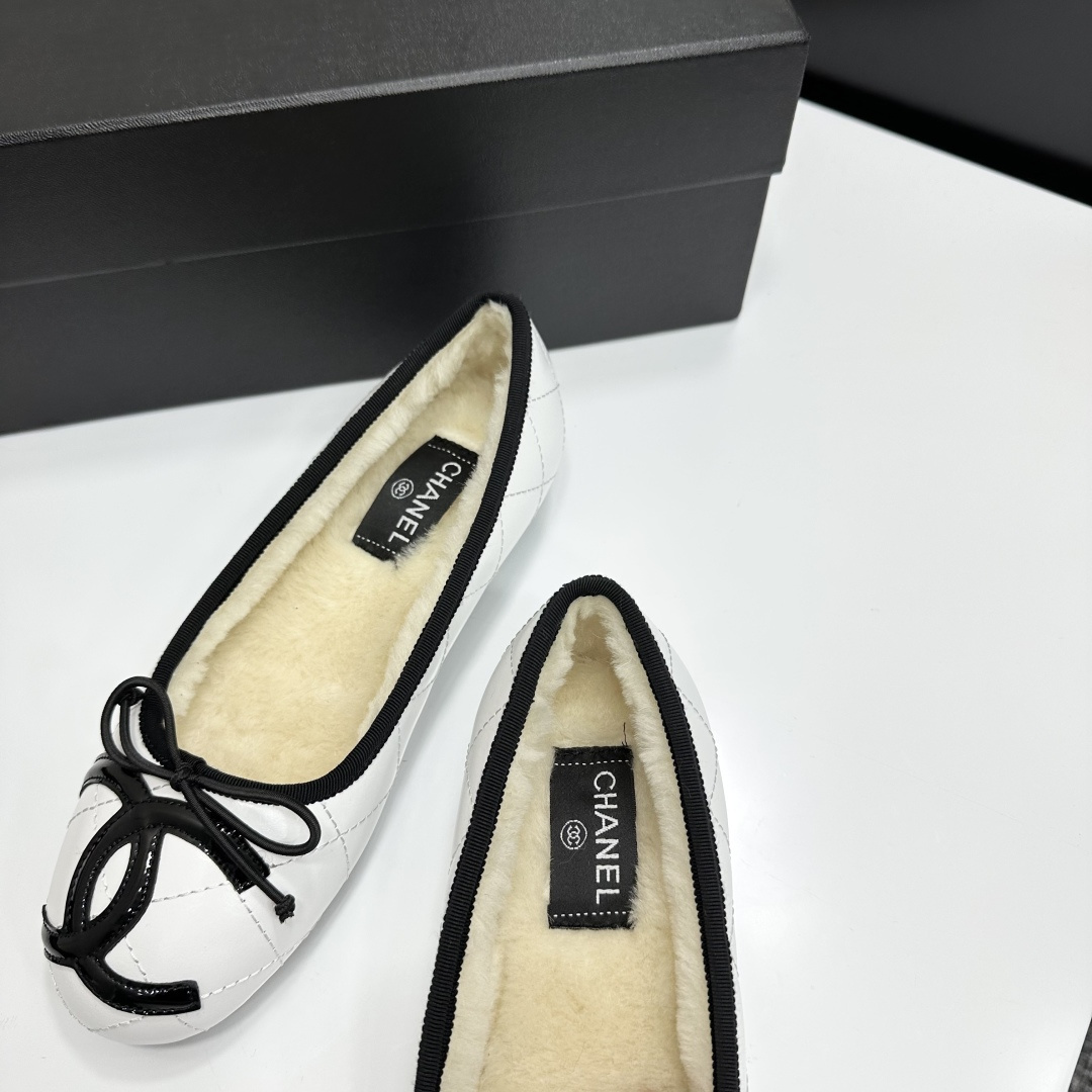 Pair of white quilted leather ballet flats with black trim and shearling lining on a black display box - Hình 6