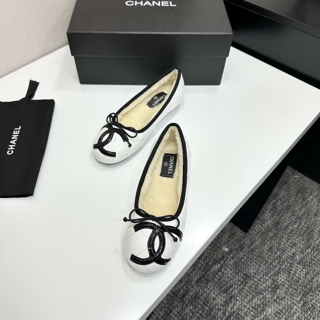 Pair of white quilted leather ballet flats with black trim and shearling lining on a black display box - Hình 5