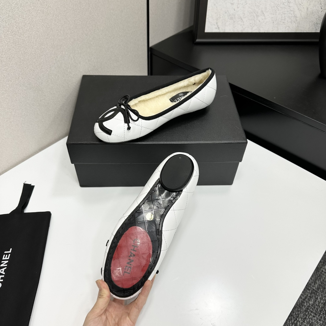 Pair of white quilted leather ballet flats with black trim and shearling lining on a black display box - Hình 4