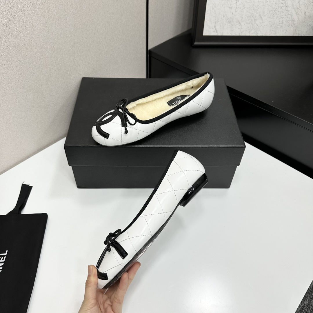 Pair of white quilted leather ballet flats with black trim and shearling lining on a black display box - Hình 3