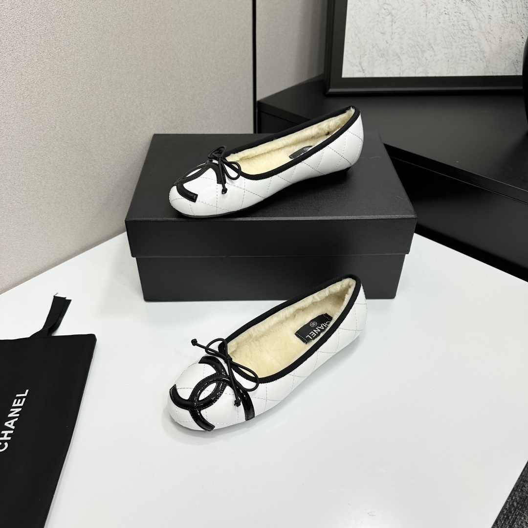 Pair of white quilted leather ballet flats with black trim and shearling lining on a black display box - Hình 2