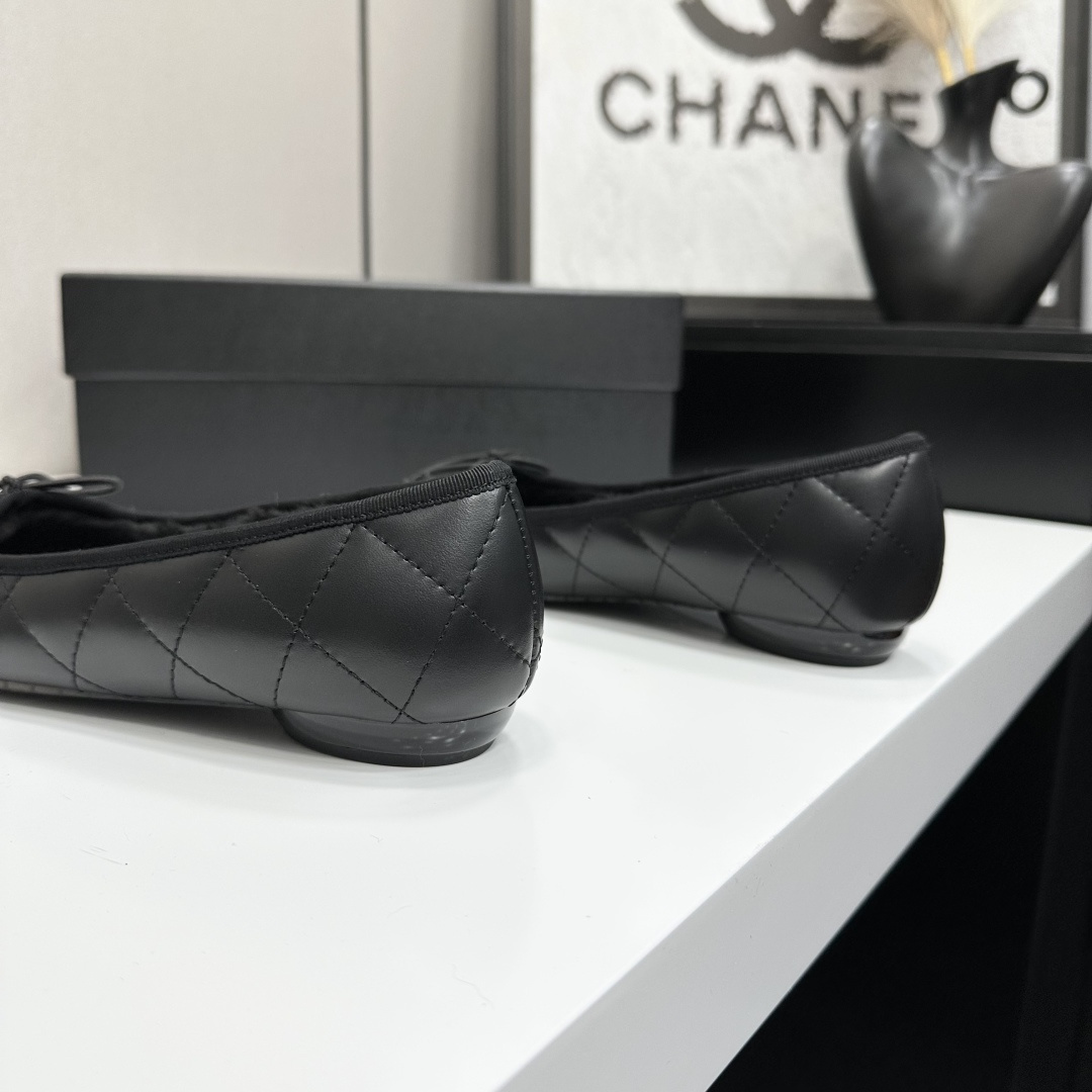 Pair of Chanel black quilted leather ballet flats with bow detail and warm interior lining on a black designer box. - Hình 7