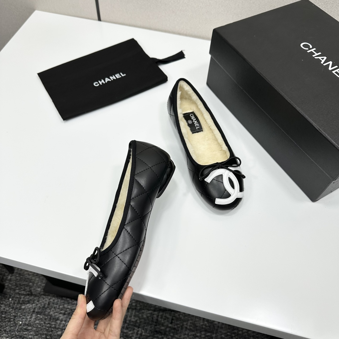 Black quilted Chanel ballet flats with white CC logo and cream shearling lining displayed on a black box. - Hình 8