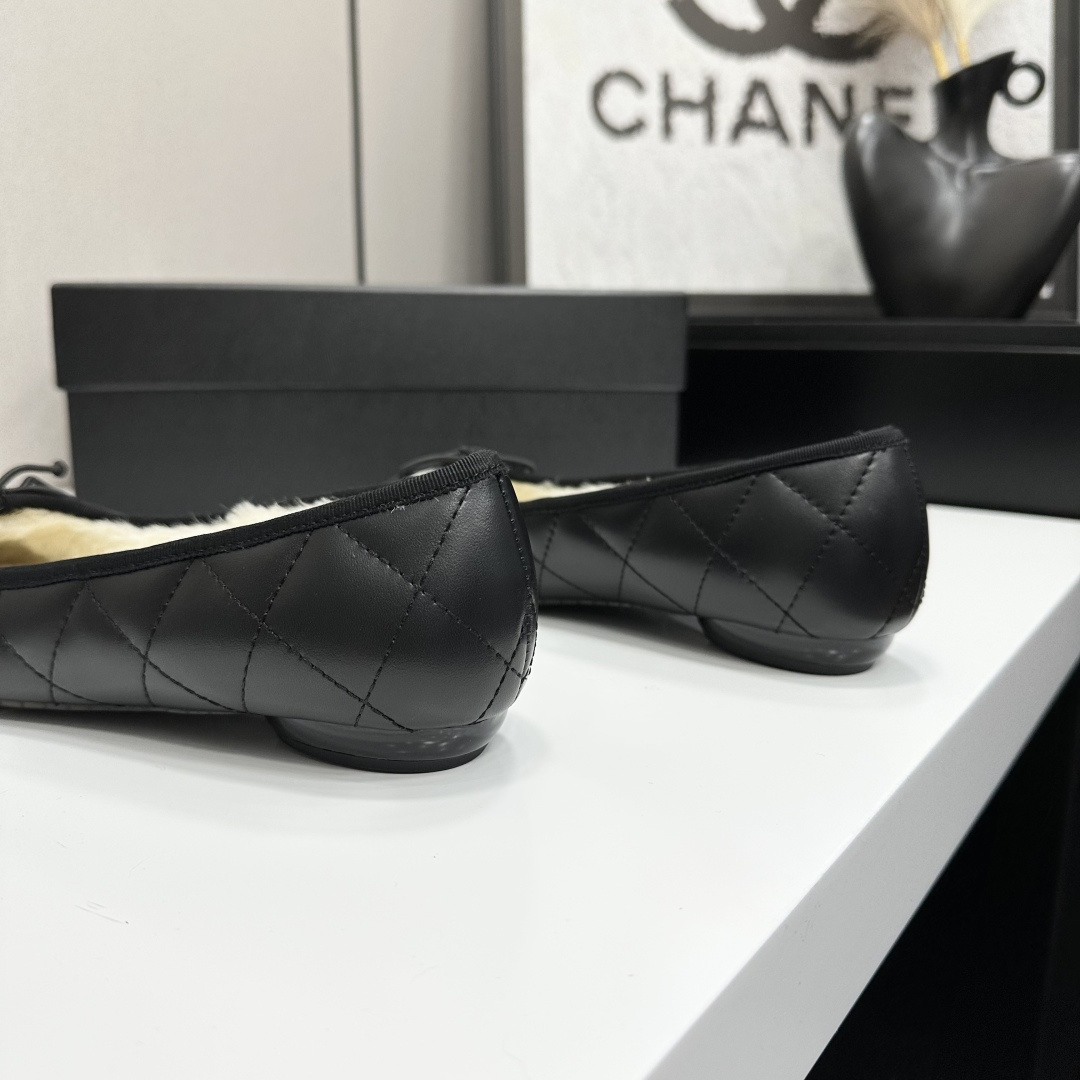 Black quilted Chanel ballet flats with white CC logo and cream shearling lining displayed on a black box. - Hình 7