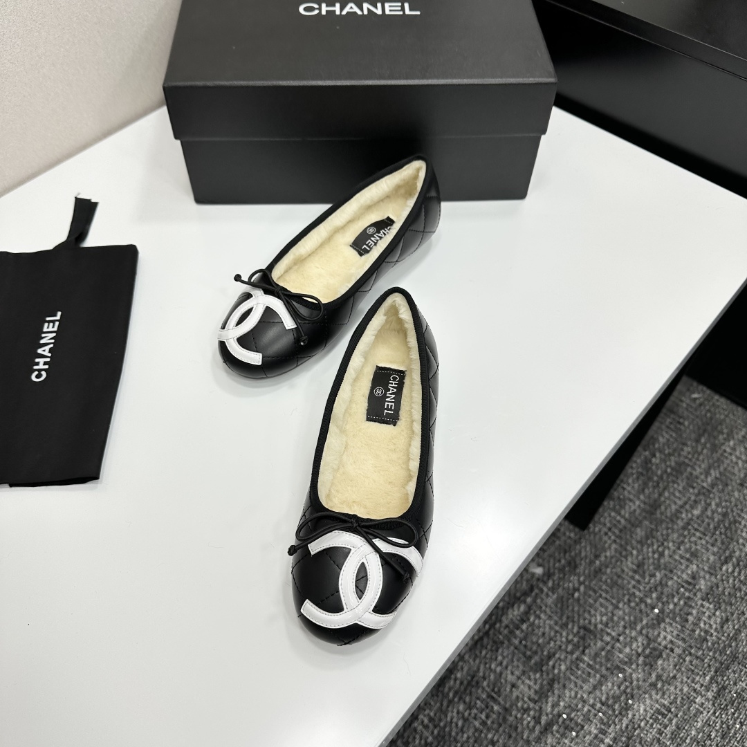 Black quilted Chanel ballet flats with white CC logo and cream shearling lining displayed on a black box. - Hình 5