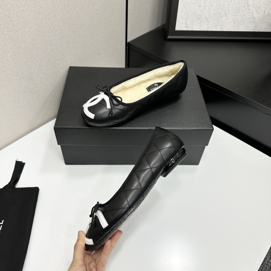 Black quilted Chanel ballet flats with white CC logo and cream shearling lining displayed on a black box. - Hình 3