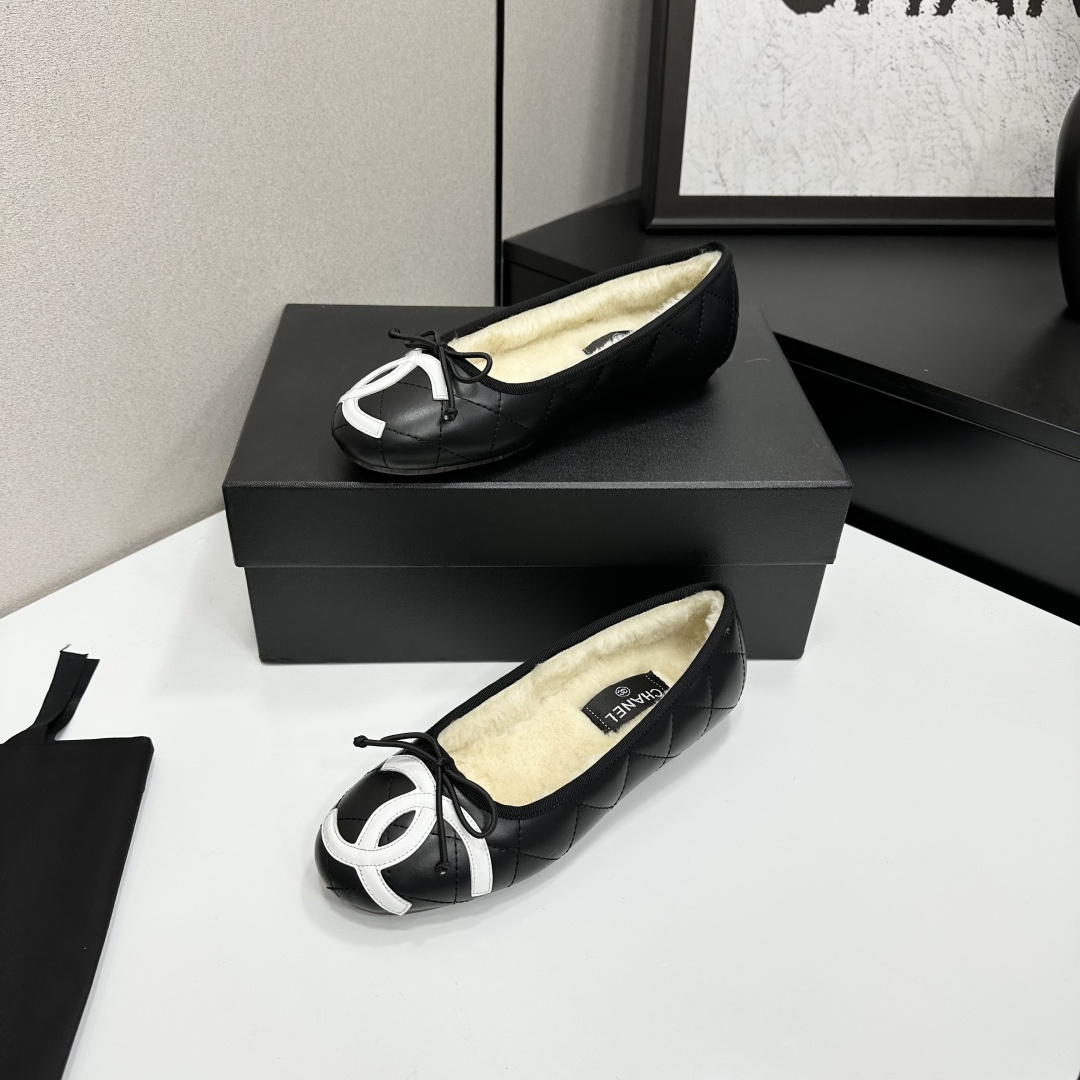 Black quilted Chanel ballet flats with white CC logo and cream shearling lining displayed on a black box. - Hình 2