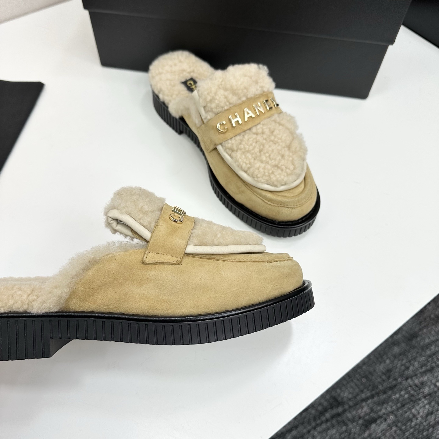 Chanel beige suede mules with cream shearling lining and gold logo strap displayed on a black box. - Hình 9