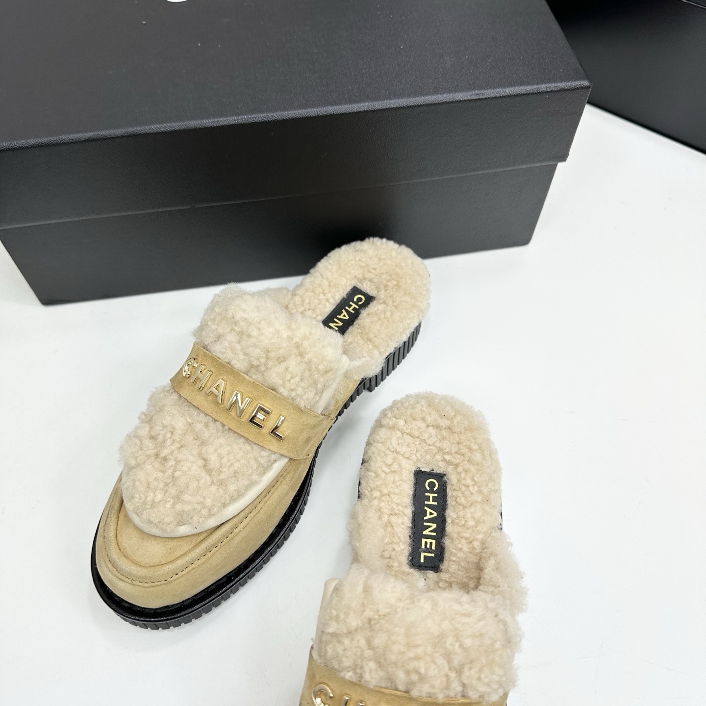 Chanel beige suede mules with cream shearling lining and gold logo strap displayed on a black box. - Hình 7