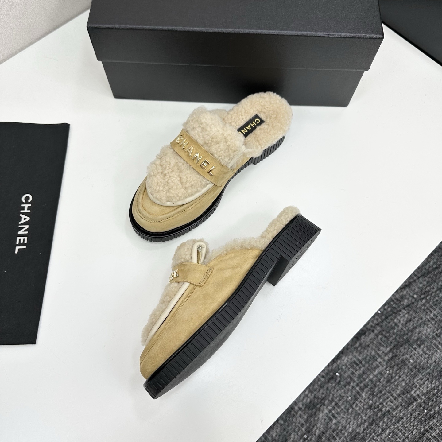 Chanel beige suede mules with cream shearling lining and gold logo strap displayed on a black box. - Hình 6