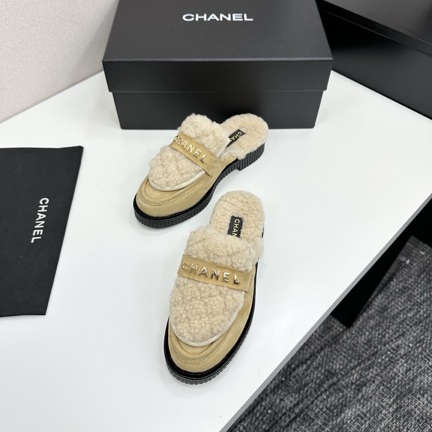 Chanel beige suede mules with cream shearling lining and gold logo strap displayed on a black box. - Hình 5
