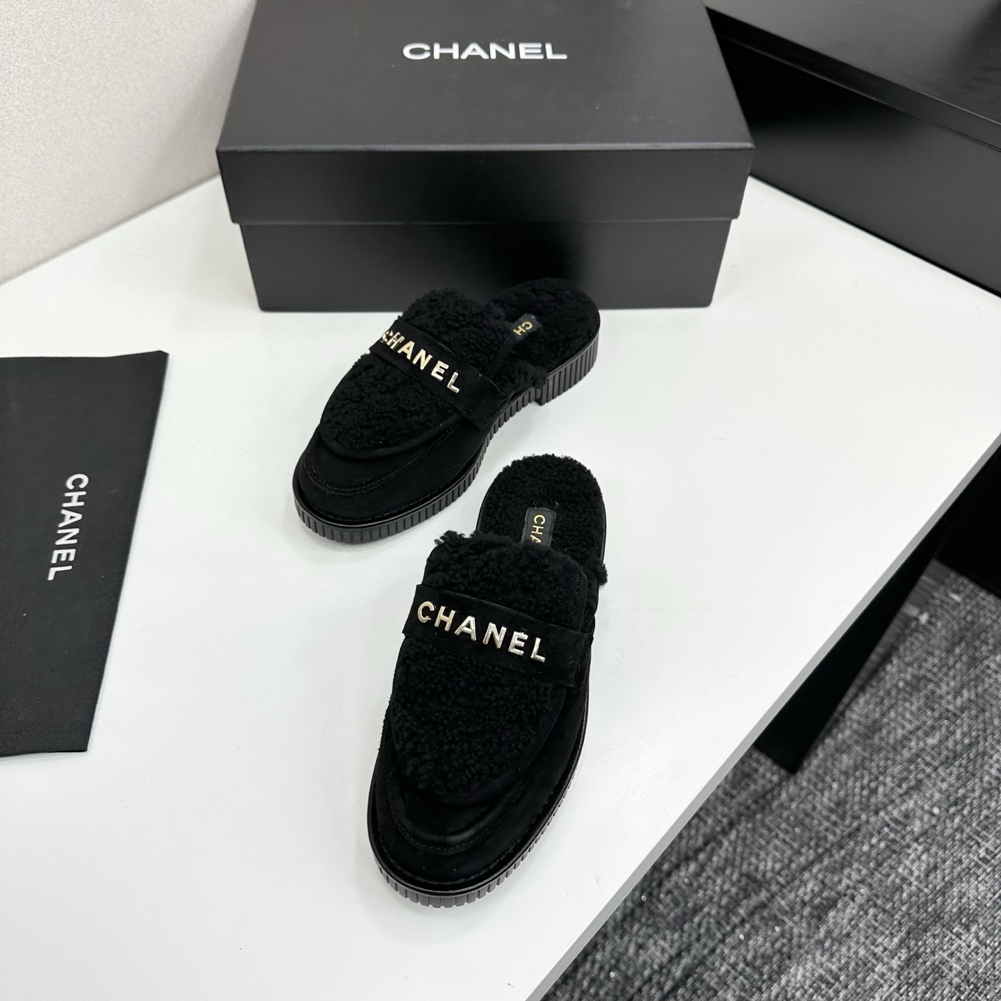A pair of luxury Chanel black suede mules with fuzzy shearling lining and gold-tone logo hardware on a black platform sole. - Hình 5