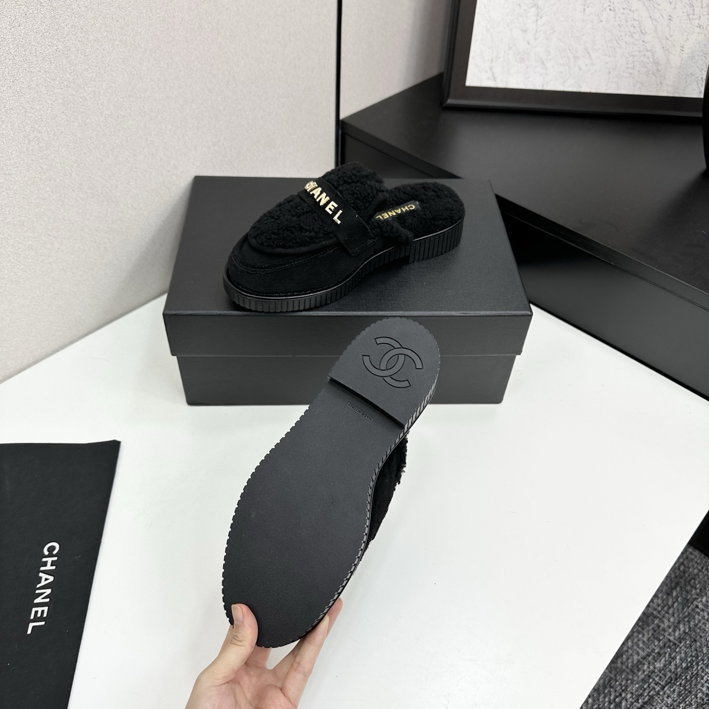 A pair of luxury Chanel black suede mules with fuzzy shearling lining and gold-tone logo hardware on a black platform sole. - Hình 4