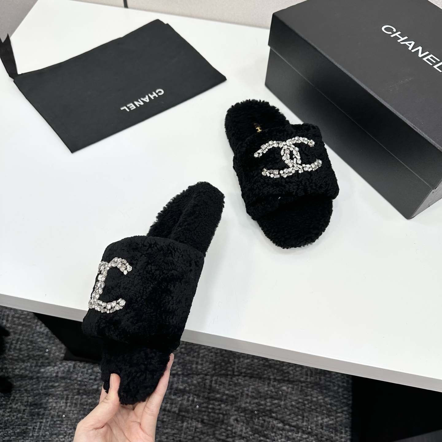 Pair of black fluffy faux fur slides featuring a sparkling crystal double C logo on a black display box. - Hình 7