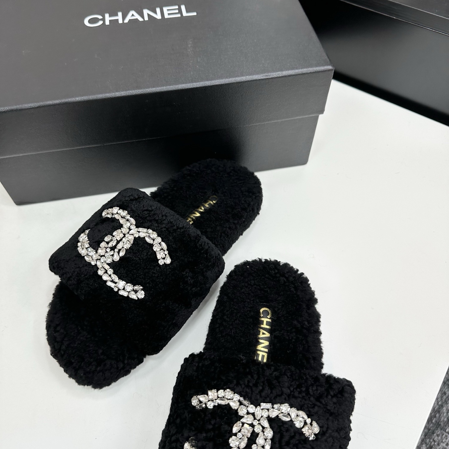 Pair of black fluffy faux fur slides featuring a sparkling crystal double C logo on a black display box. - Hình 6
