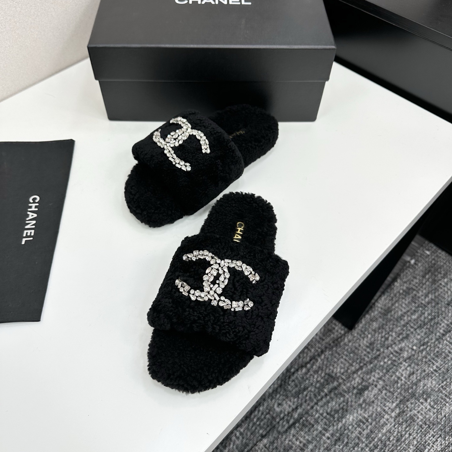 Pair of black fluffy faux fur slides featuring a sparkling crystal double C logo on a black display box. - Hình 5