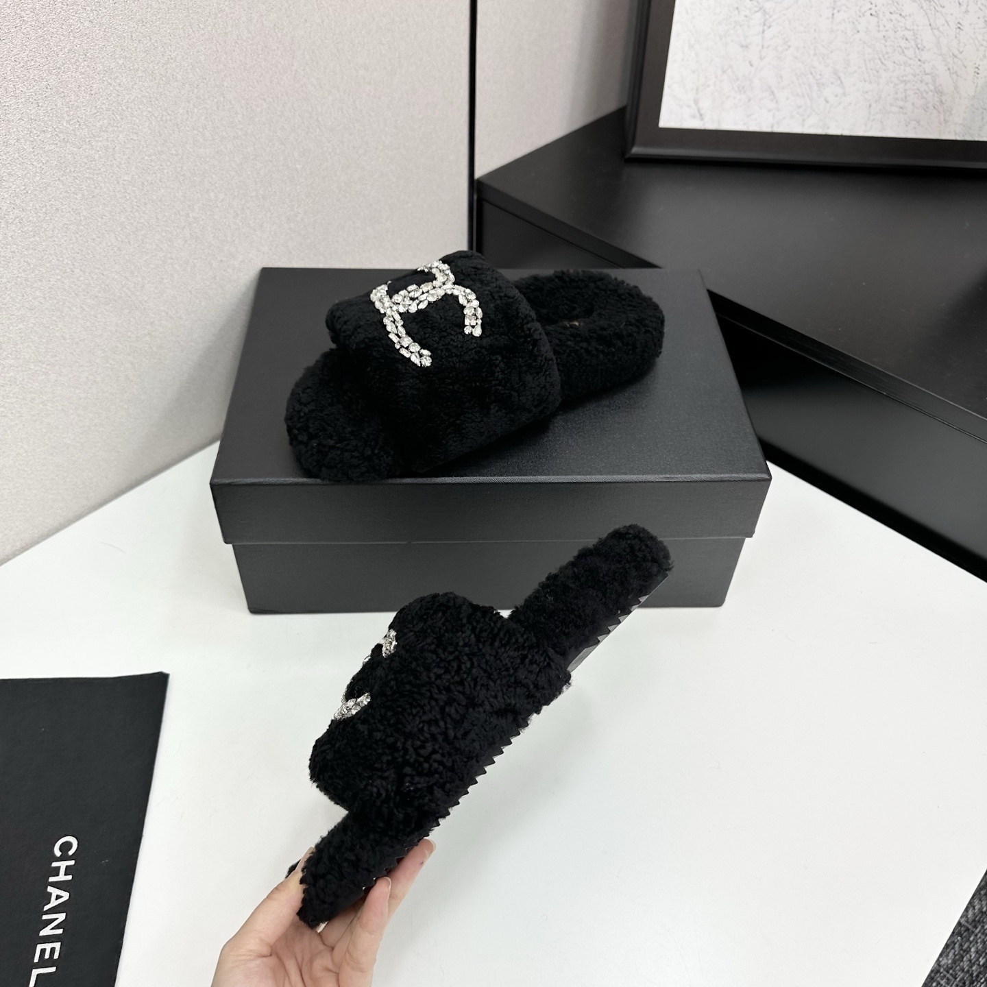 Pair of black fluffy faux fur slides featuring a sparkling crystal double C logo on a black display box. - Hình 3