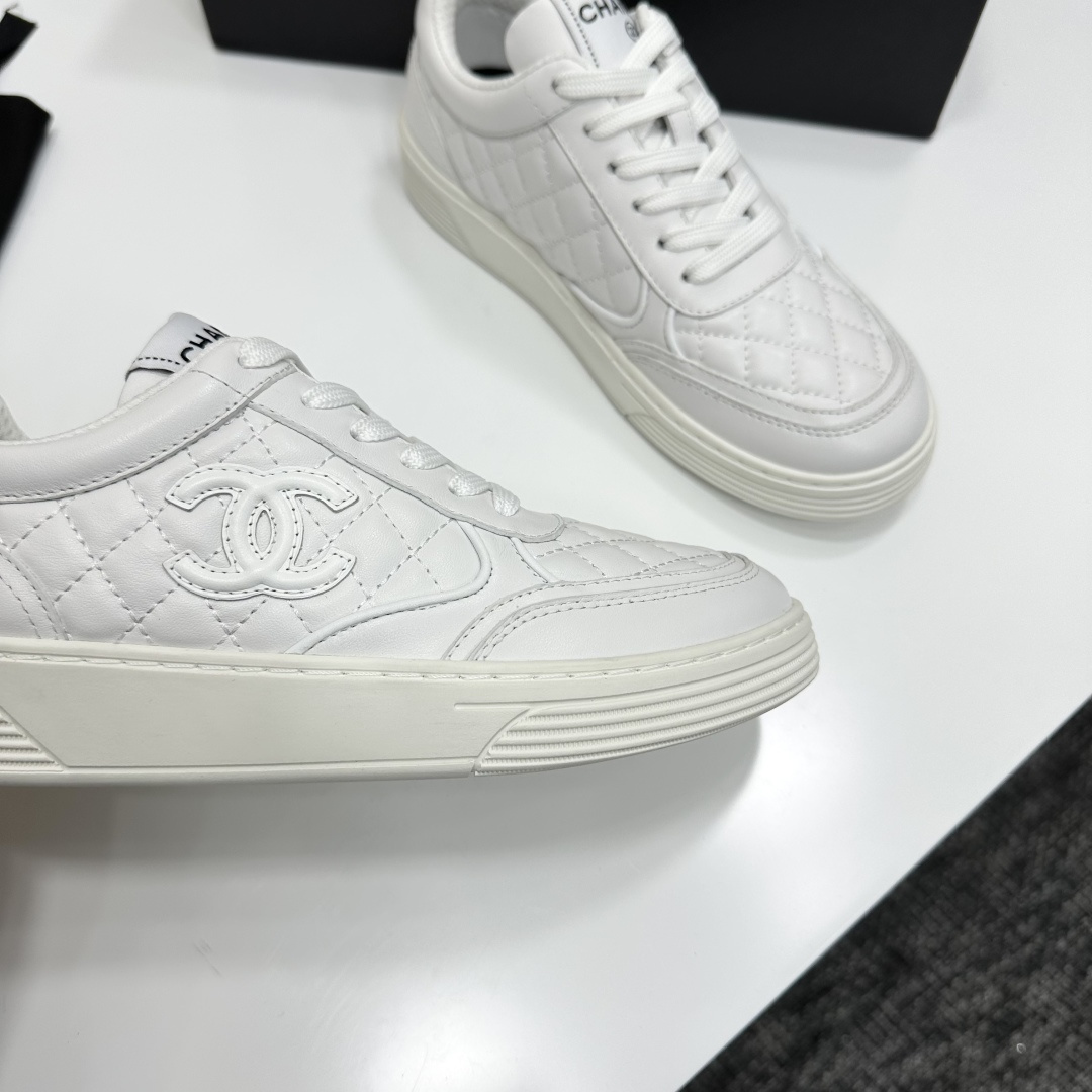 Side view of white Chanel quilted leather sneakers with interlocking CC logo and platform sole on a black box - Hình 3