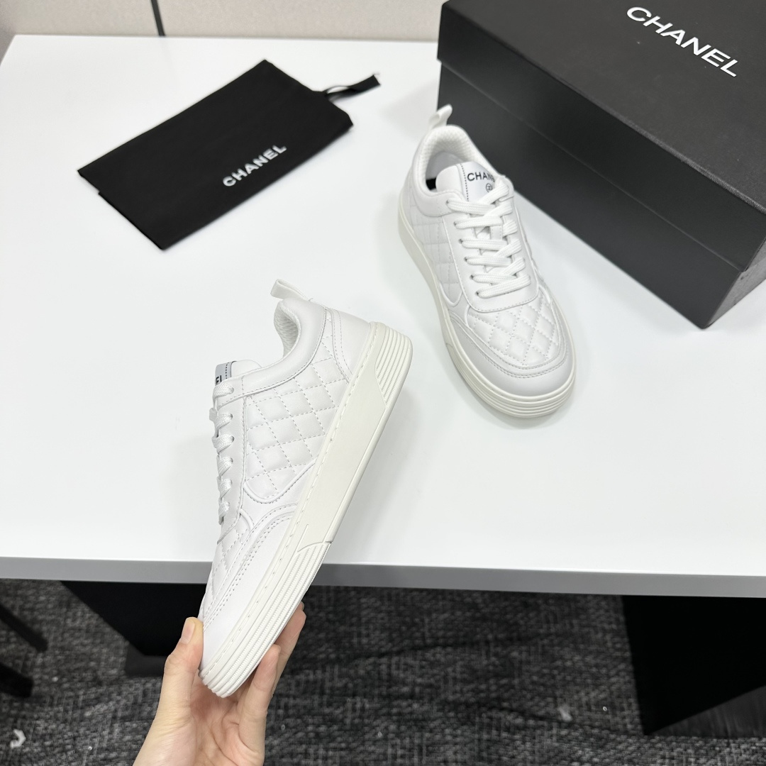 Side view of white Chanel quilted leather sneakers with interlocking CC logo and platform sole on a black box - Hình 2