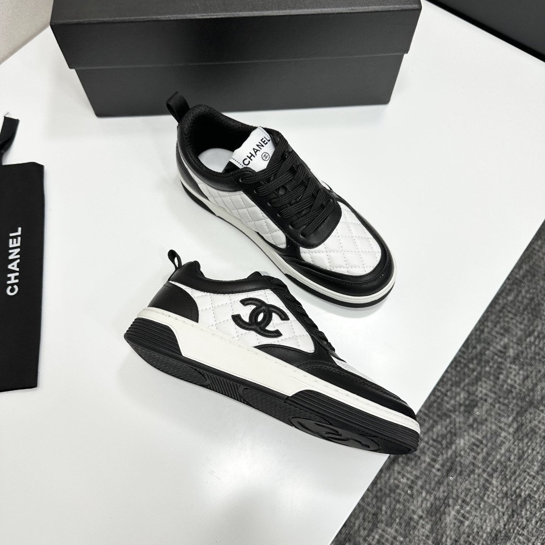 A pair of Chanel black and white quilted leather sneakers featuring the iconic CC logo on the side, displayed on a black box. - Hình 10