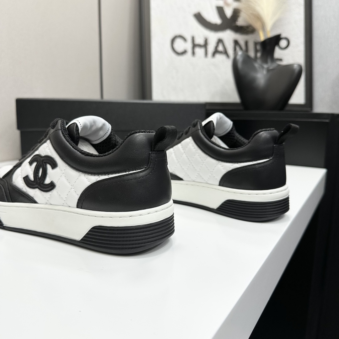 A pair of Chanel black and white quilted leather sneakers featuring the iconic CC logo on the side, displayed on a black box. - Hình 9