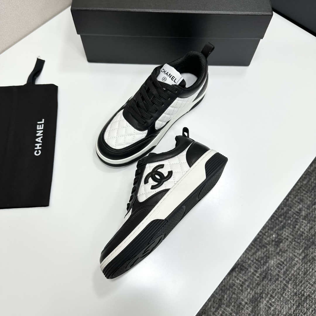 A pair of Chanel black and white quilted leather sneakers featuring the iconic CC logo on the side, displayed on a black box. - Hình 7