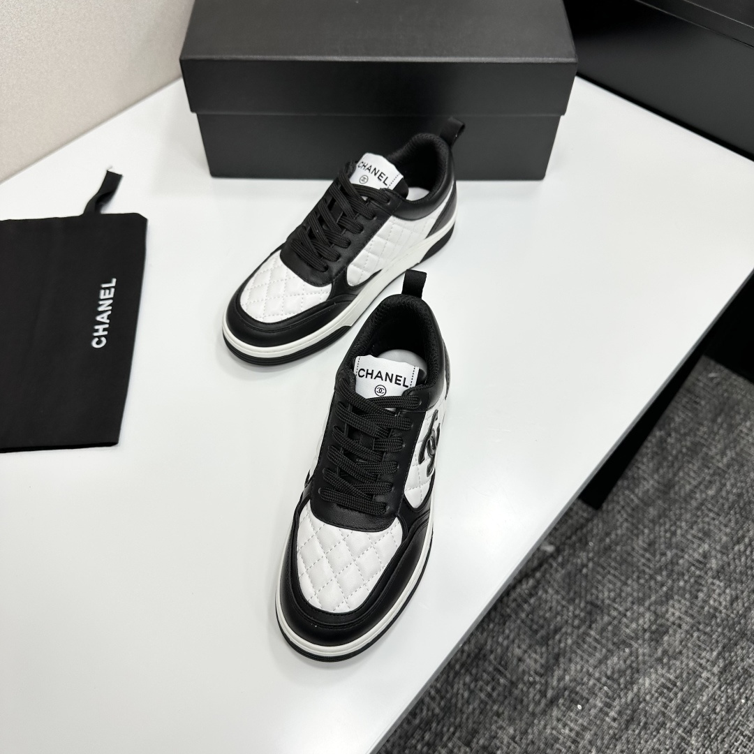 A pair of Chanel black and white quilted leather sneakers featuring the iconic CC logo on the side, displayed on a black box. - Hình 6