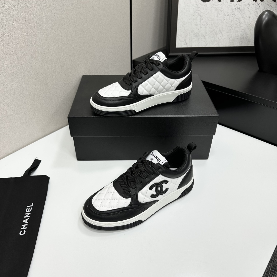 A pair of Chanel black and white quilted leather sneakers featuring the iconic CC logo on the side, displayed on a black box. - Hình 3