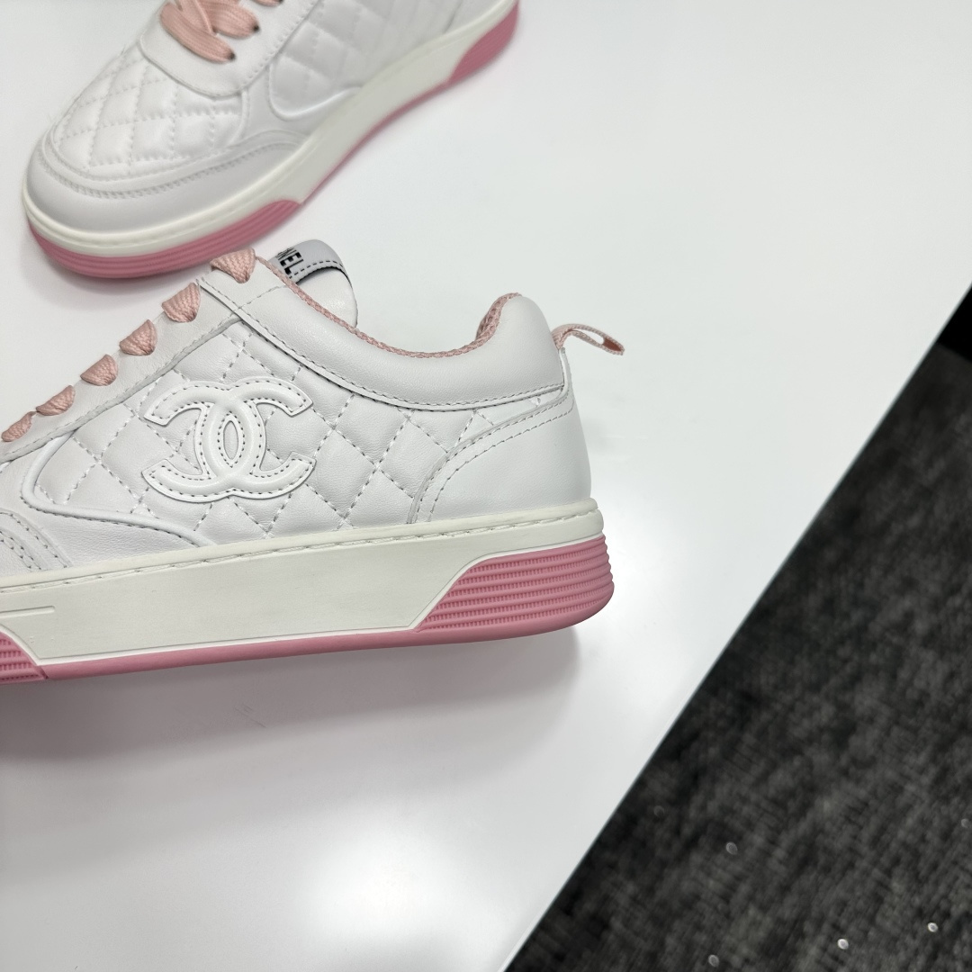 A pair of Chanel white quilted leather sneakers with pink laces and pink outsoles displayed on a black box. - Hình 9