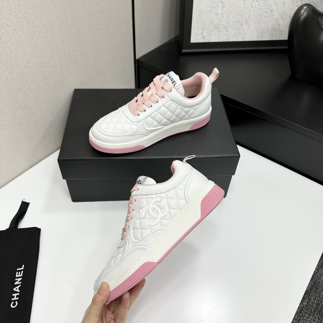 A pair of Chanel white quilted leather sneakers with pink laces and pink outsoles displayed on a black box. - Hình 5