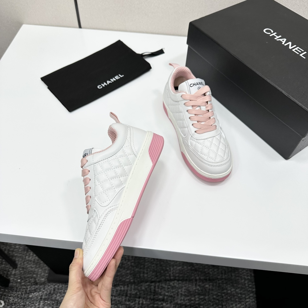 A pair of Chanel white quilted leather sneakers with pink laces and pink outsoles displayed on a black box. - Hình 3