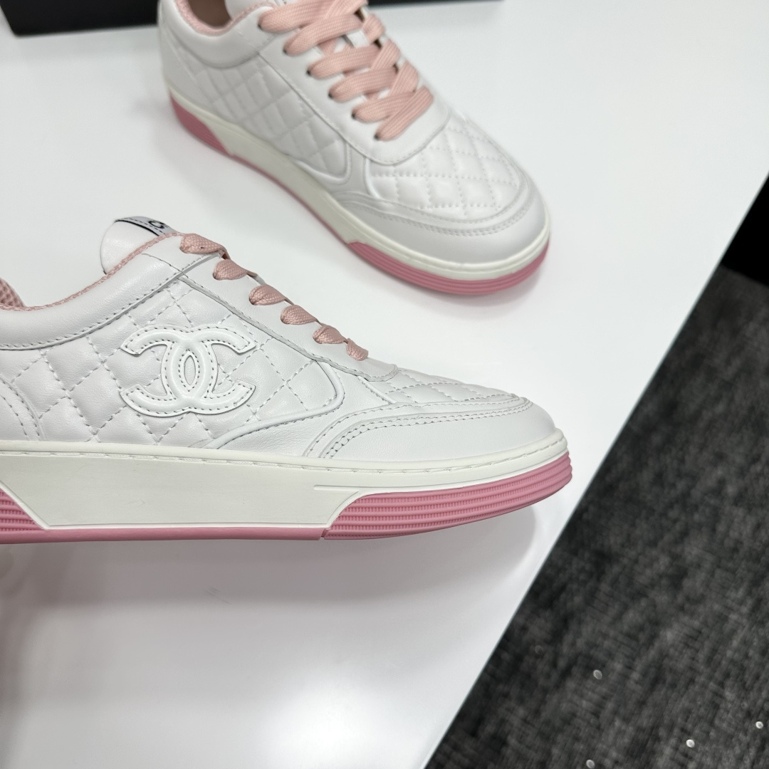 A pair of Chanel white quilted leather sneakers with pink laces and pink outsoles displayed on a black box. - Hình 2