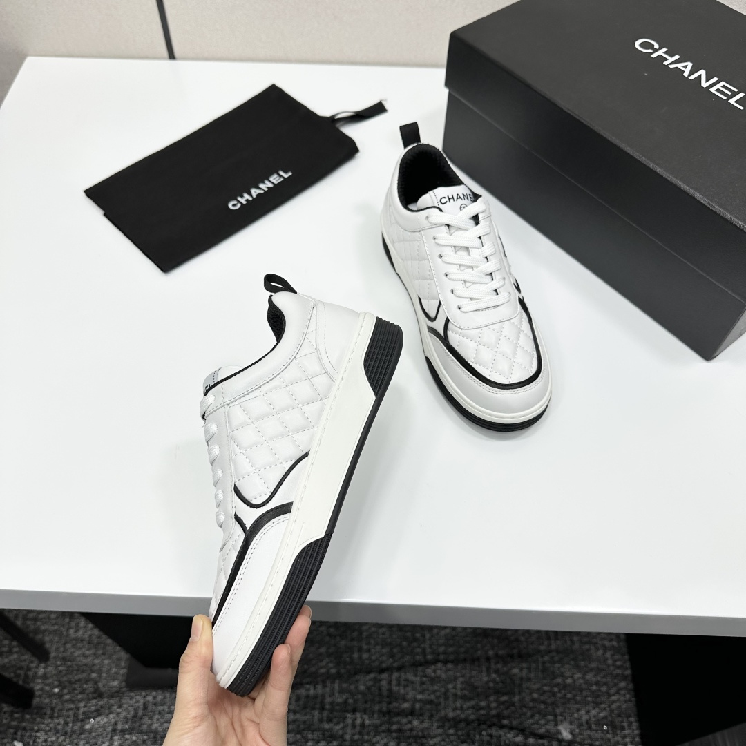 A pair of white quilted leather sneakers with black interlocking logo and trim displayed on a black box - Hình 10