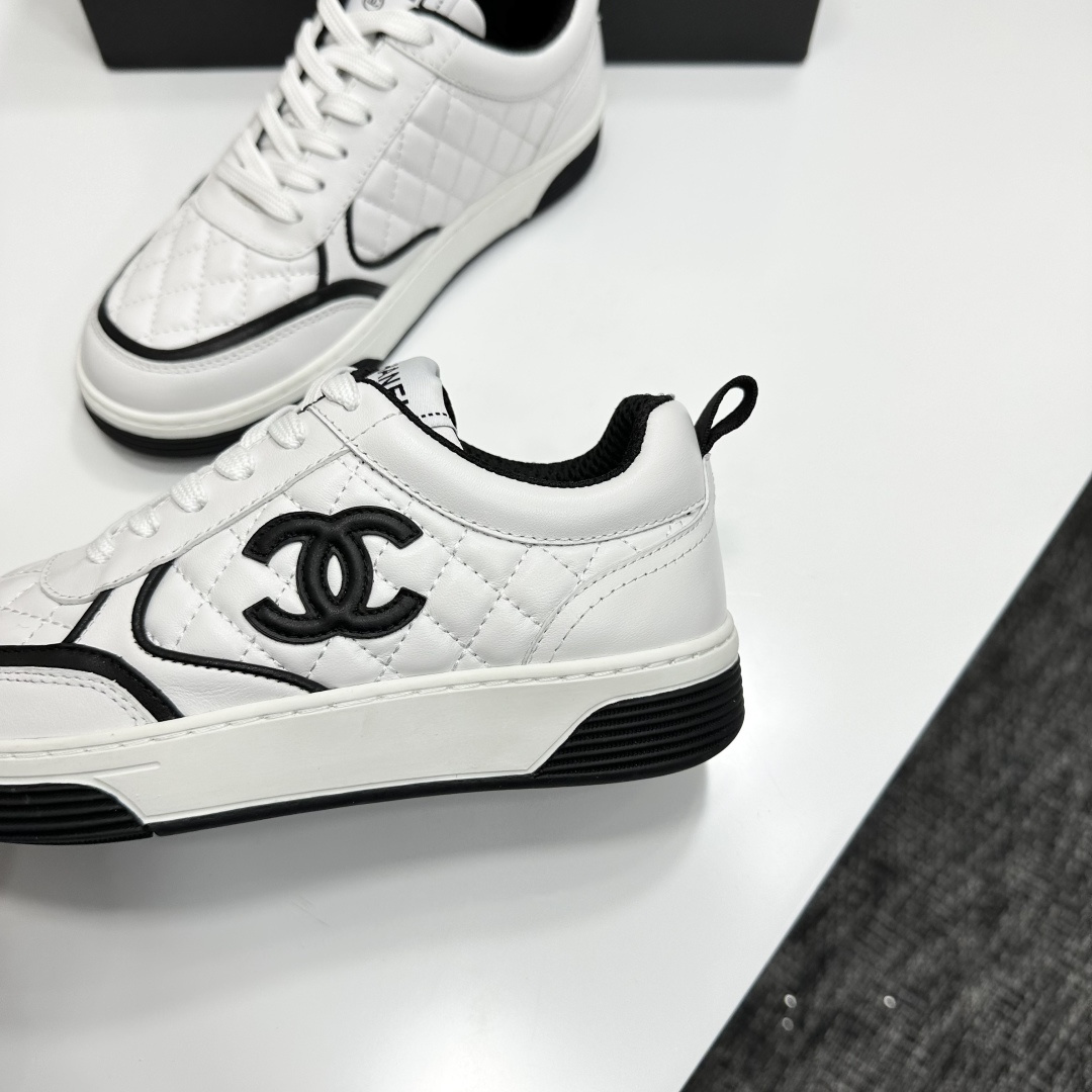 A pair of white quilted leather sneakers with black interlocking logo and trim displayed on a black box - Hình 8