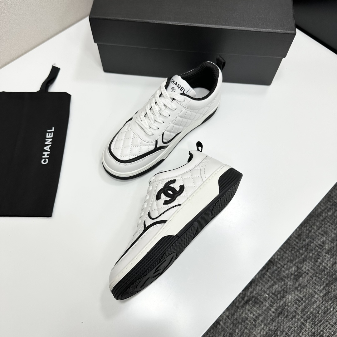 A pair of white quilted leather sneakers with black interlocking logo and trim displayed on a black box - Hình 7
