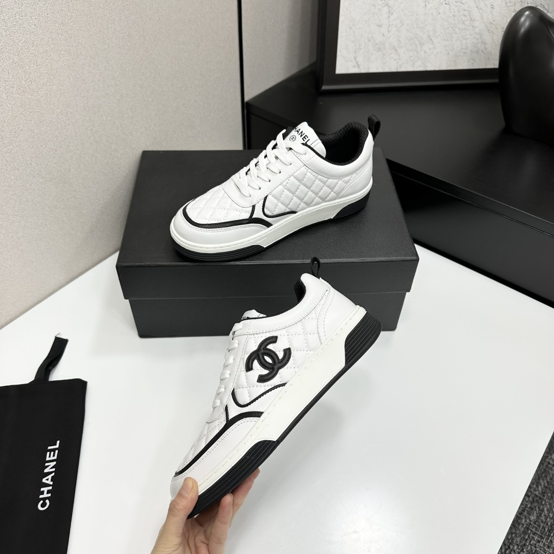 A pair of white quilted leather sneakers with black interlocking logo and trim displayed on a black box - Hình 4