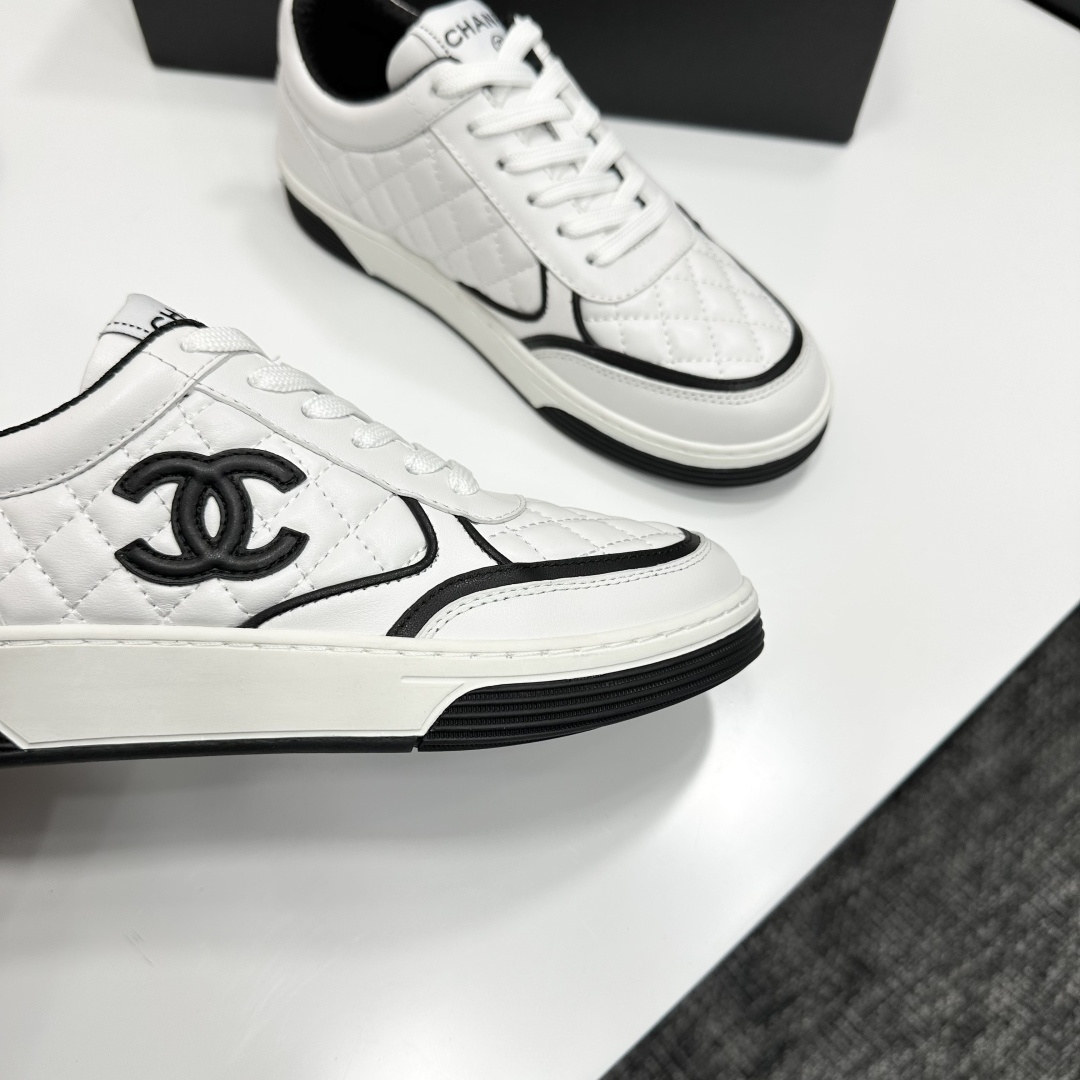 A pair of white quilted leather sneakers with black interlocking logo and trim displayed on a black box - Hình 2