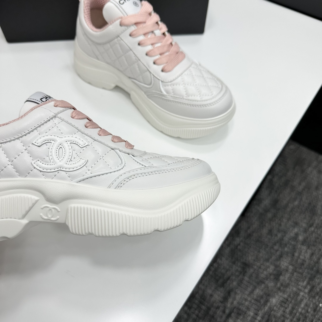 A pair of luxury Chanel white quilted platform sneakers with pink laces and pink interior lining displayed on a black box. - Hình 10