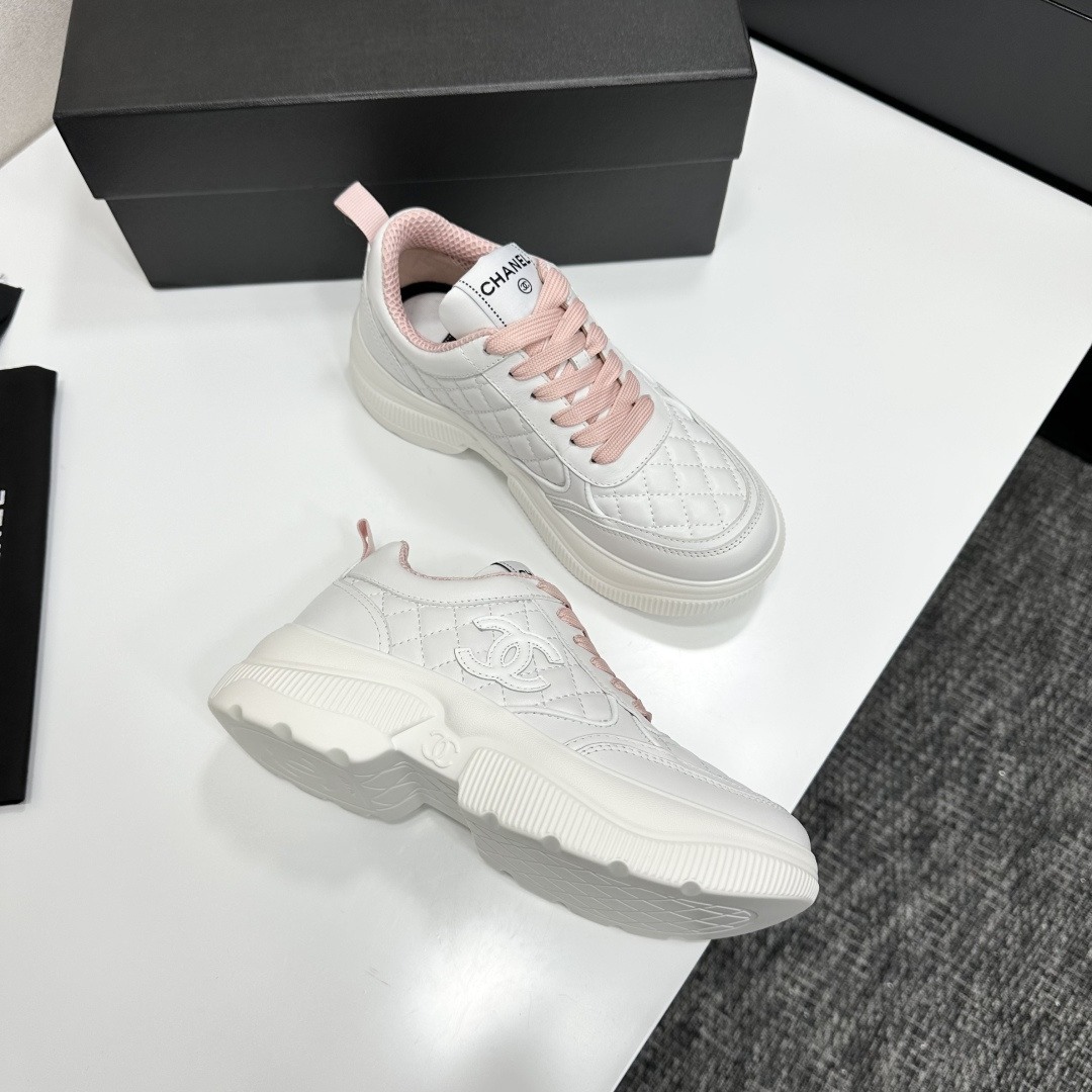 A pair of luxury Chanel white quilted platform sneakers with pink laces and pink interior lining displayed on a black box. - Hình 9