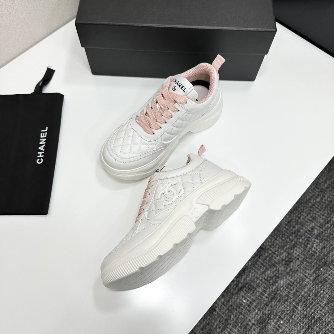 A pair of luxury Chanel white quilted platform sneakers with pink laces and pink interior lining displayed on a black box. - Hình 7